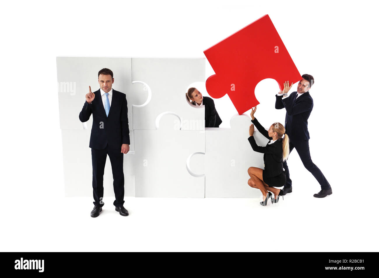 L'équipe d'assemblage grand puzzle et smart businessman standing côté pinting doigt isolé sur fond blanc Banque D'Images