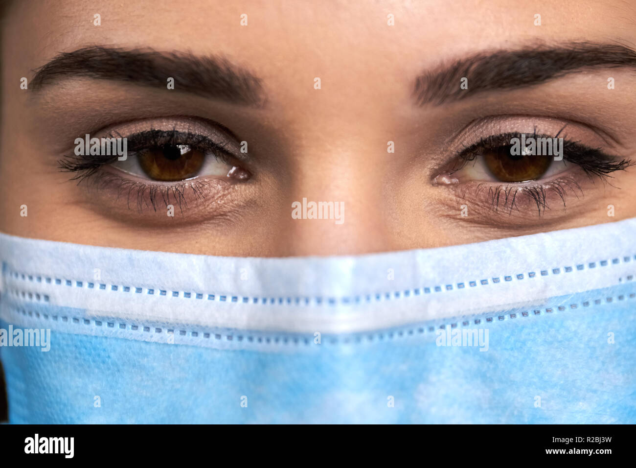 Close up femme médecin en masque de visage. Les yeux noisette de jolie médecin en masque médical. Beaux yeux humains. Banque D'Images