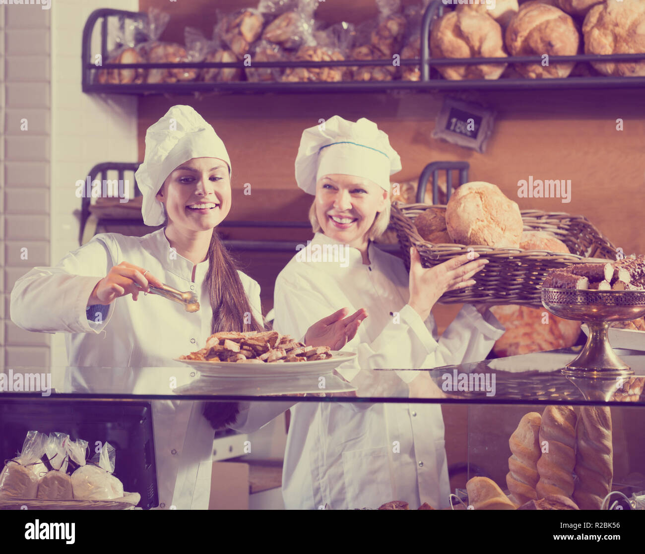 Deux femmes gaies vendeur la pâtisserie fraîche et miches de pain". Se concentrer sur la jeune femme Banque D'Images