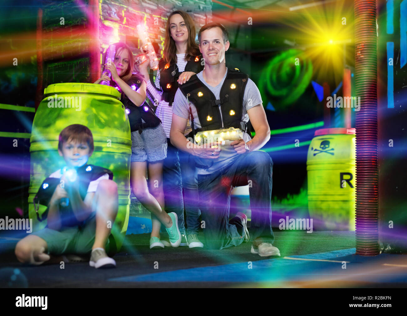 Portrait d'enfants heureux et leurs parents avec des armes à laser poutres couleur laser tag pendant le jeu dans une pièce sombre Banque D'Images