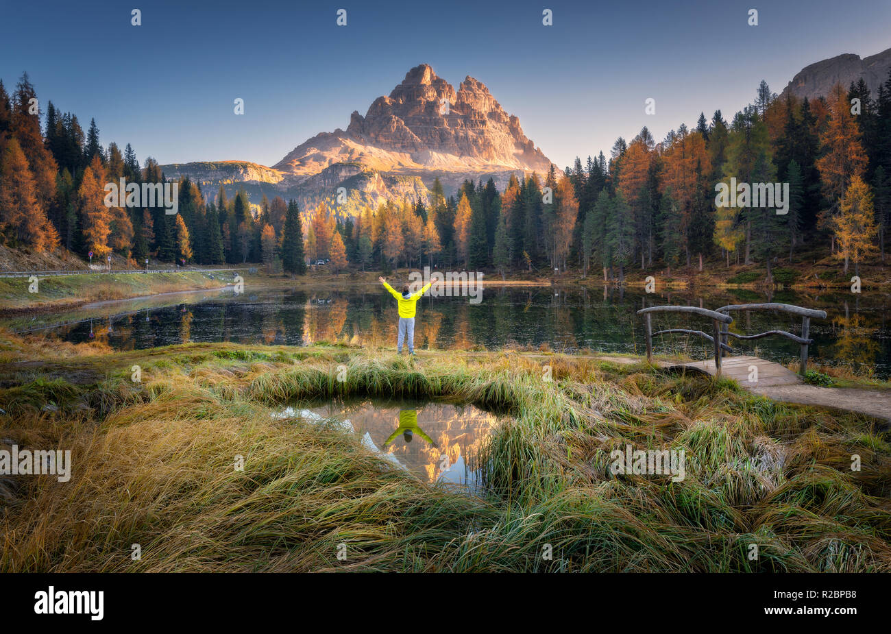 L'homme avec les armes sur Antorno lake avec la réflexion des Tre Cime di Lavaredo au lever du soleil à l'automne en Dolomites, Italie. Paysage avec homme heureux, gr Banque D'Images