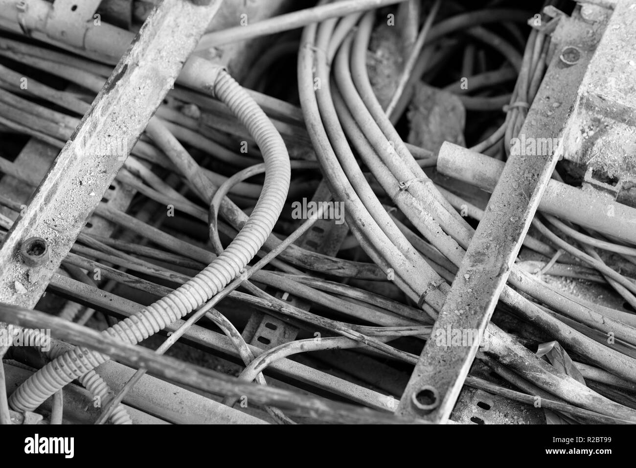 Le conduit de câble électrique ouvert, montrant différentes épaisseurs, avec une apparence sale dans un environnement industriel, en attente d'être supprimé. Le noir et blanc ph Banque D'Images