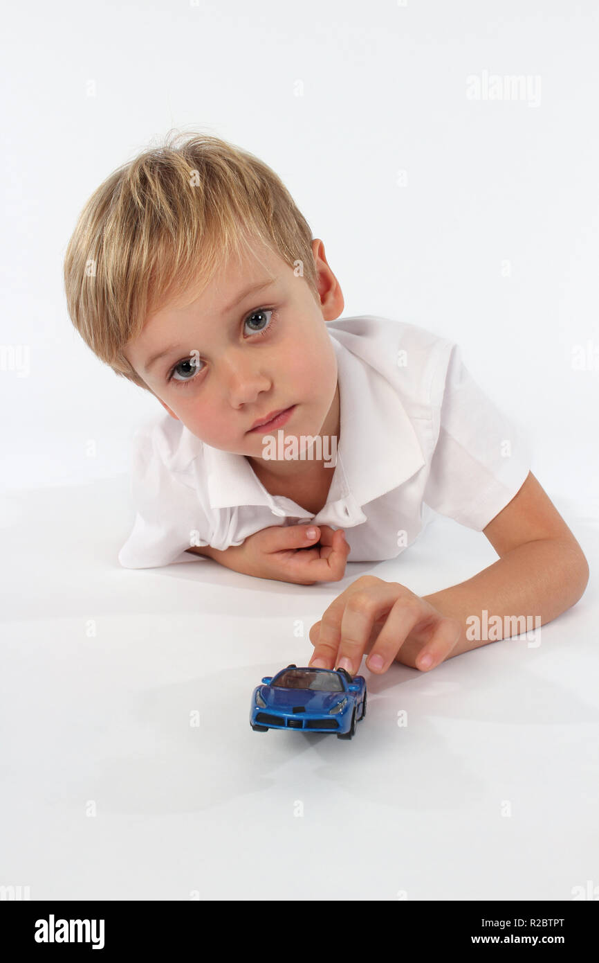 Cute blonde blue eyed petit Garçon jouant avec des jouets de voiture Banque D'Images