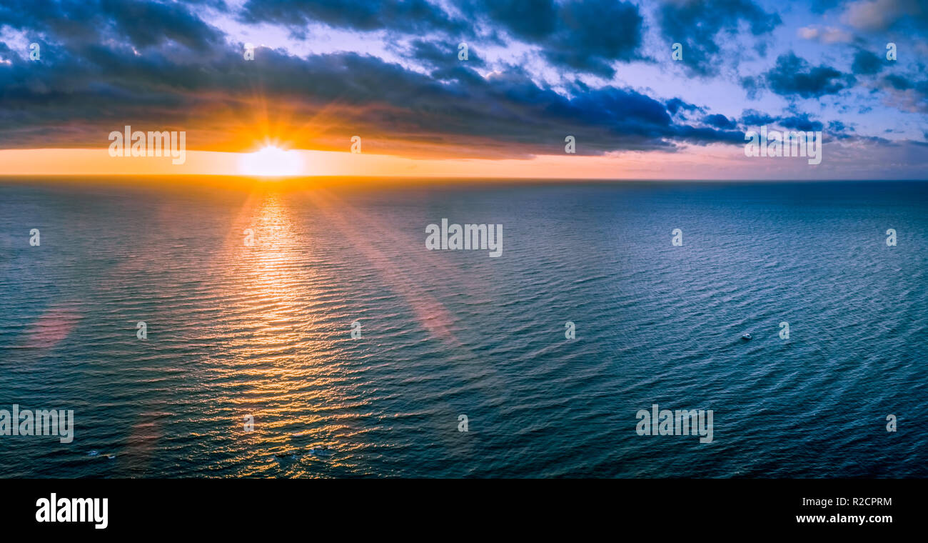 Bateau solitaire dans l'océan au coucher du soleil - as large panorama aérien Banque D'Images