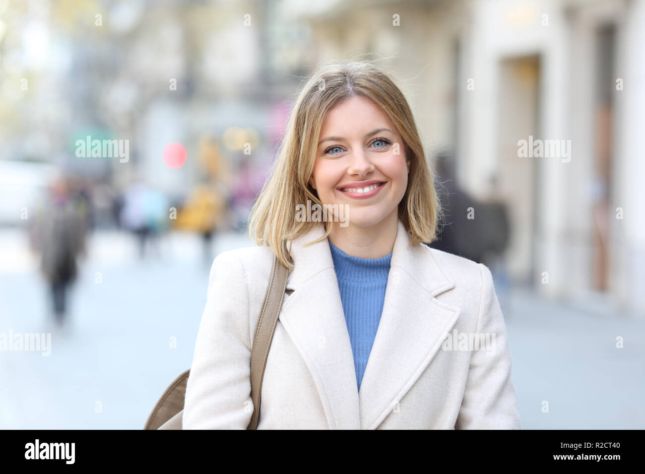 Vue avant portrait of a happy woman looking at camera debout dans la rue Banque D'Images