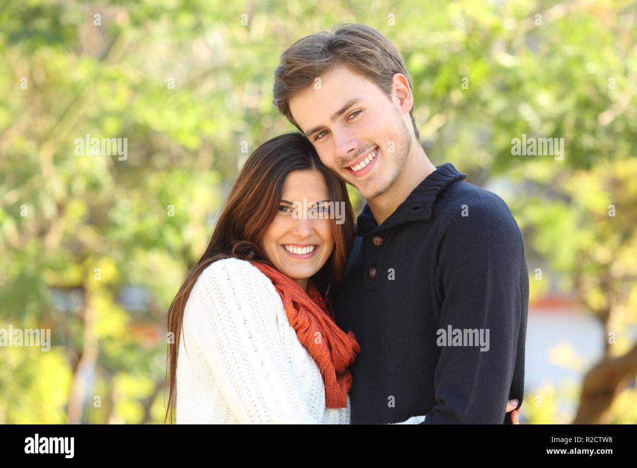 Couple heureux en amour posing looking at camera dans un parc avec un fond vert Banque D'Images