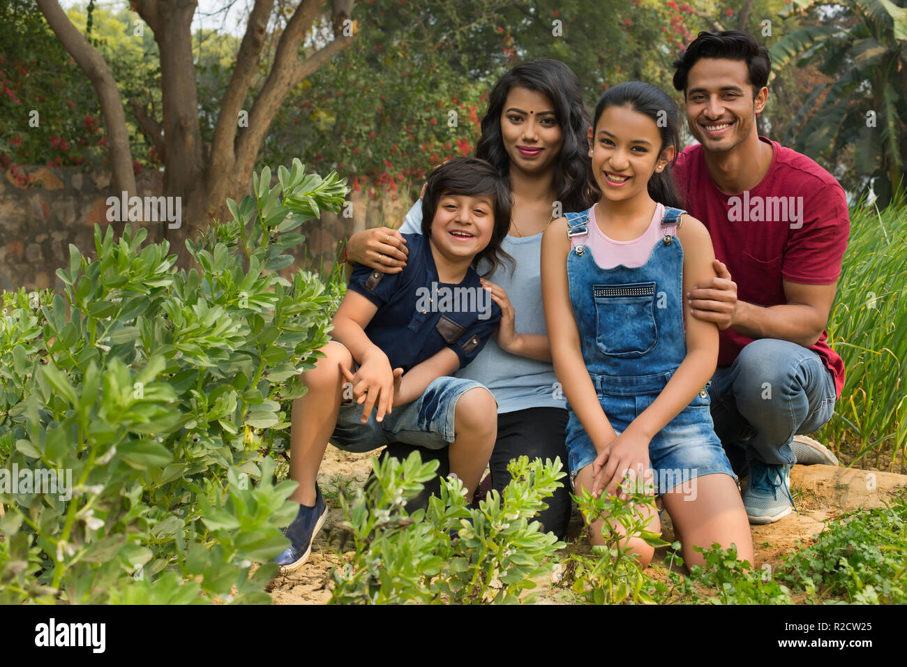 Heureuse famille des homme femme son fils et sa fille assis dans un jardin et posant. Banque D'Images