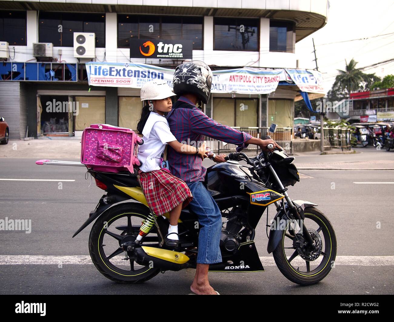 ANTIPOLO CITY, PHILIPPINES - 12 NOVEMBRE 2018 : Un homme et sa fille la moto et attend le feu vert à une intersection. Banque D'Images