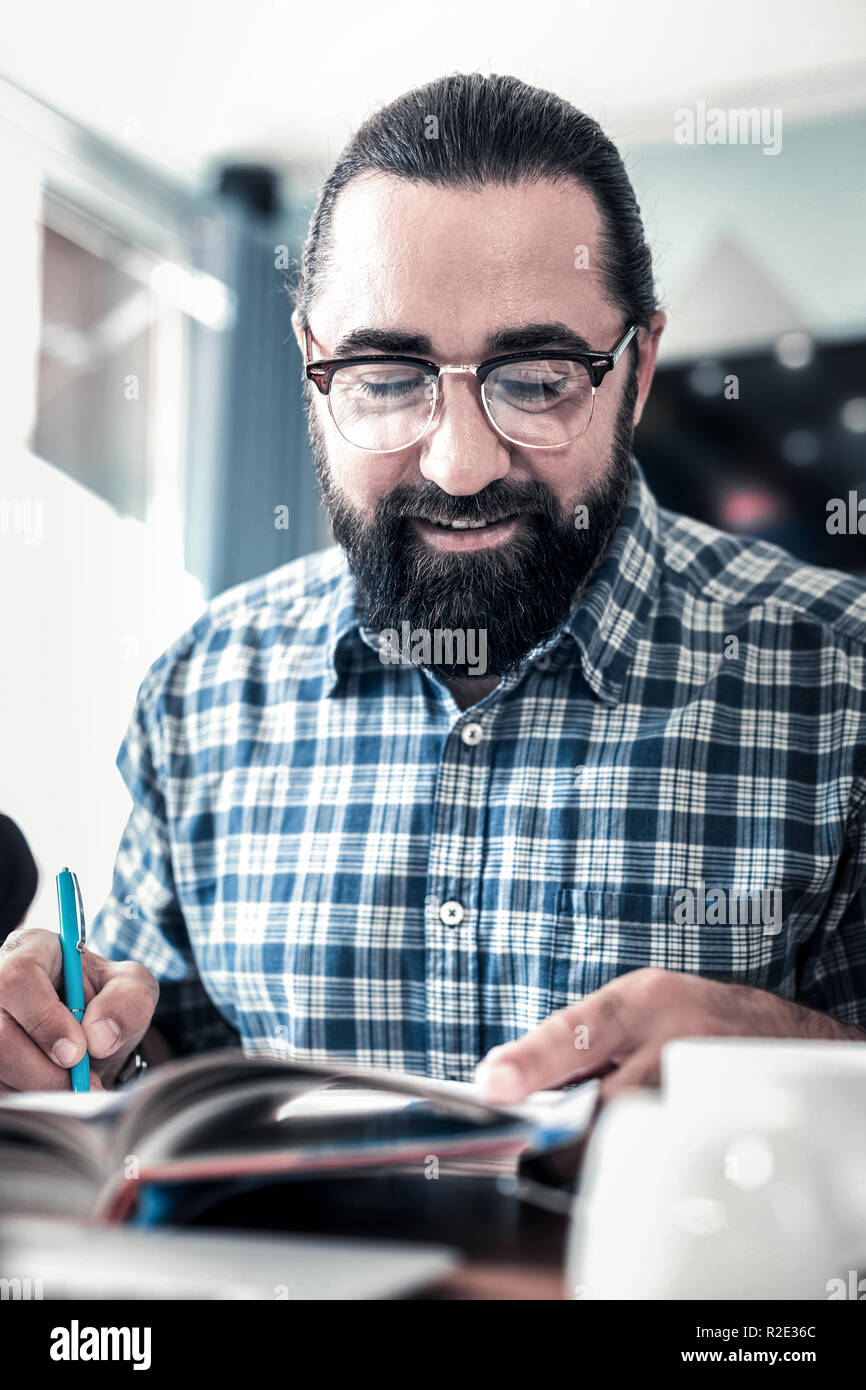 Dark-haired pigiste holding blue pen travaillant dur Banque D'Images