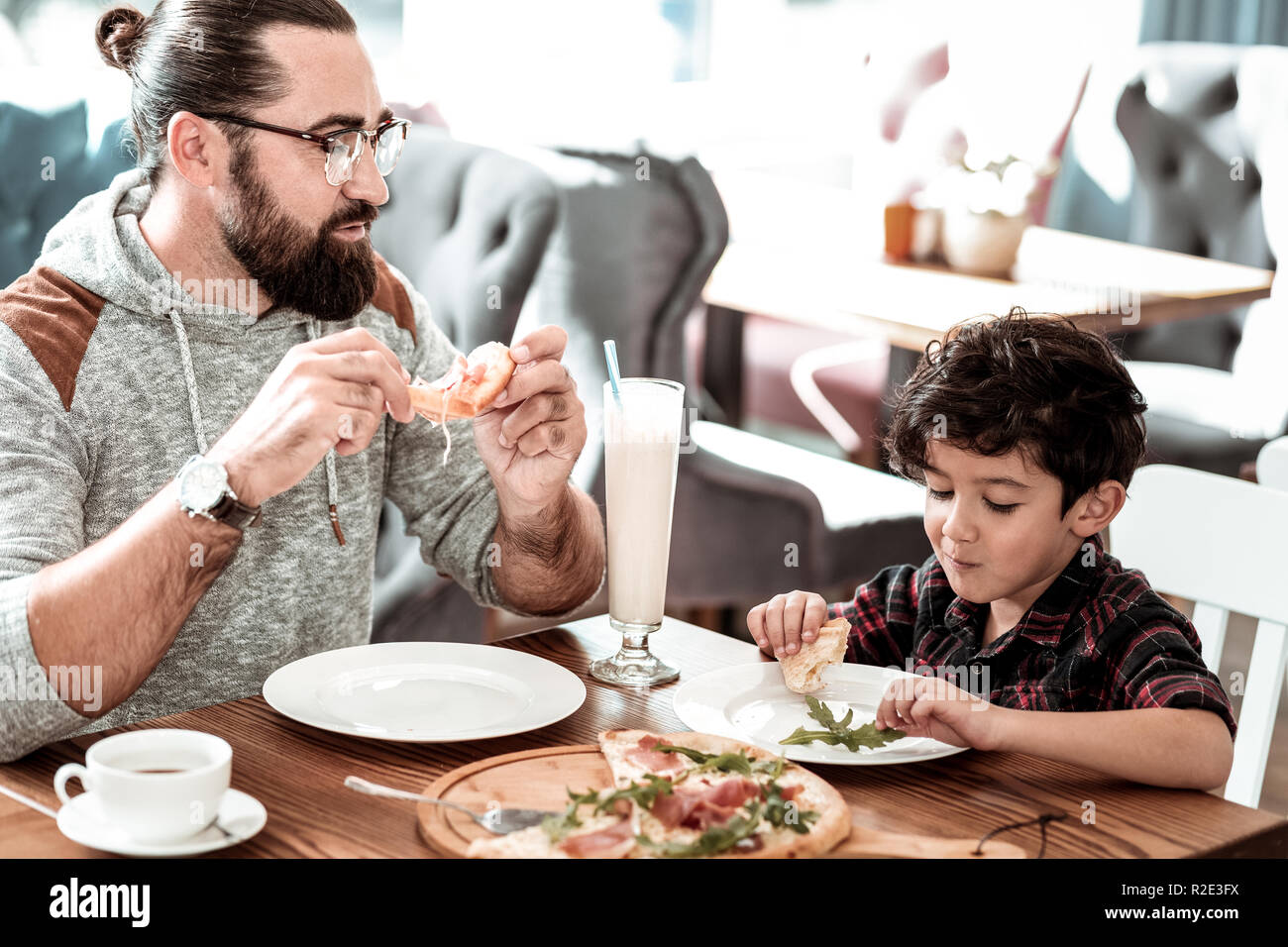 Père barbu et mignon drôle fils s'amusant eating pizza together Banque D'Images