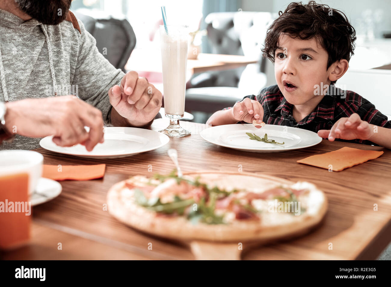 Dark-eyed transmission curly boy se sentir heureux de manger la pizza avec le père Banque D'Images
