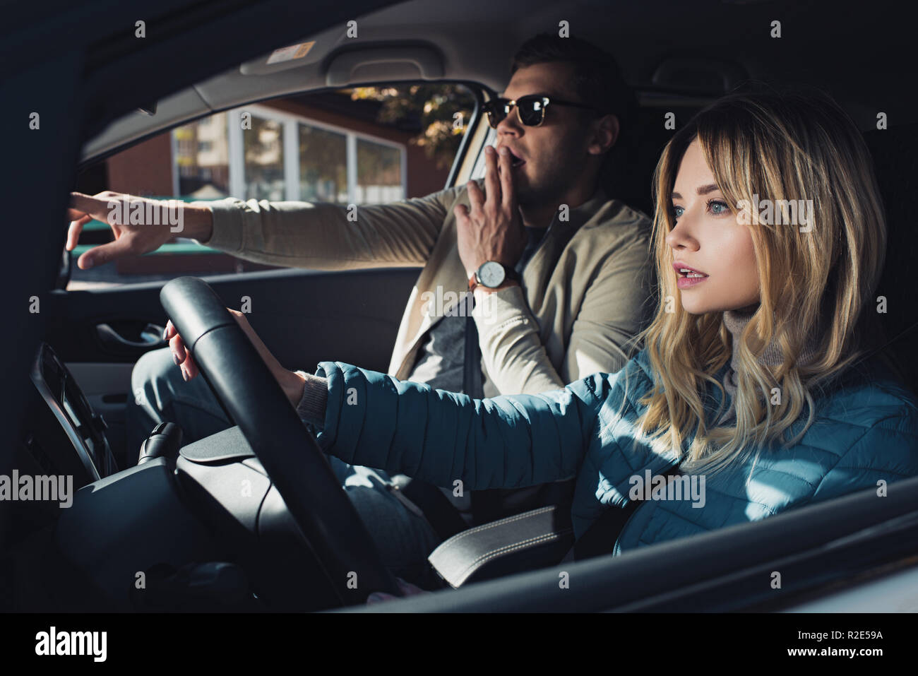 Choqué man showing direction pour petite amie sur le siège du conducteur dans la voiture Banque D'Images