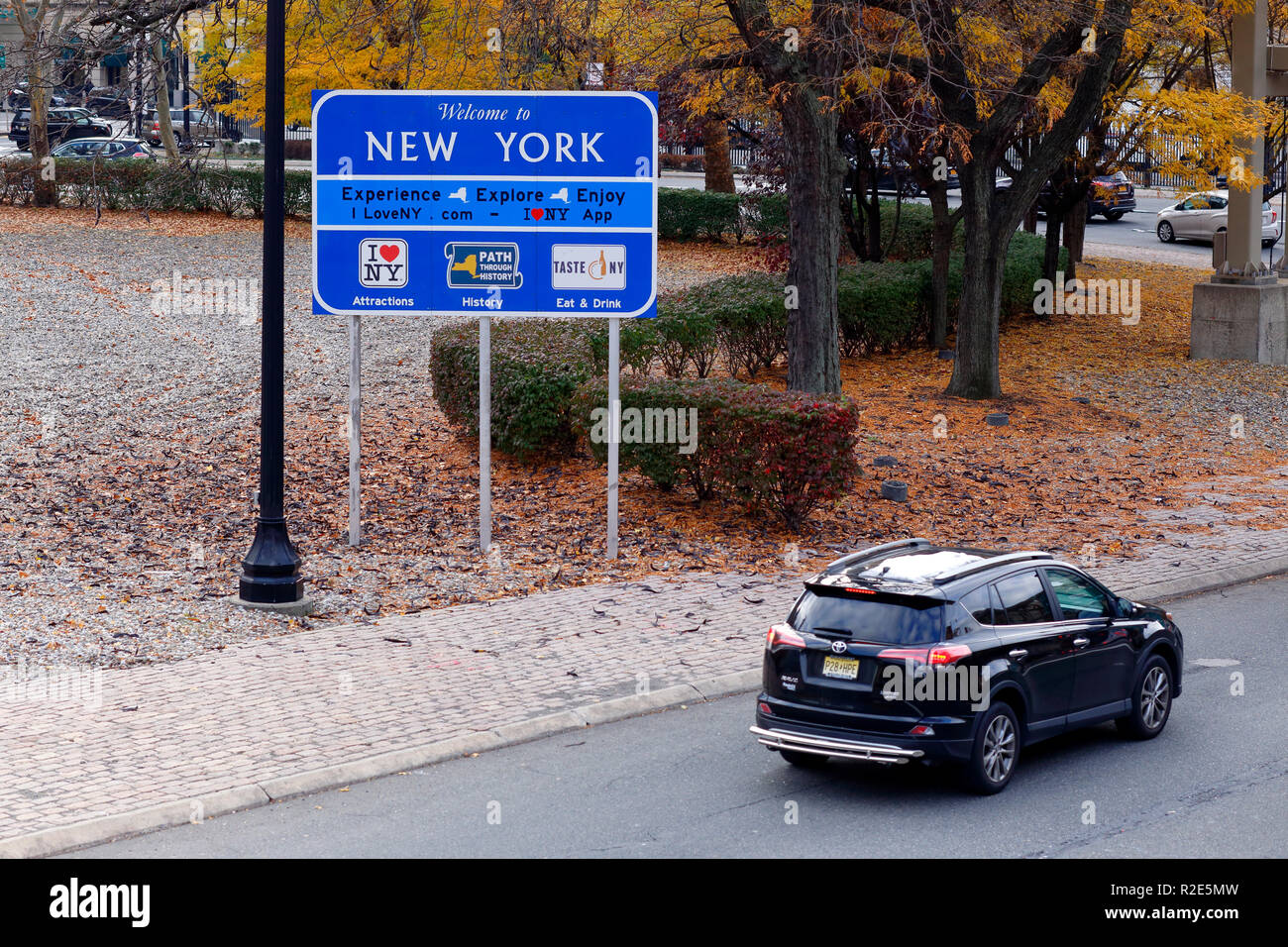 Une voiture conduit un passé Bienvenue à New York road sign Banque D'Images