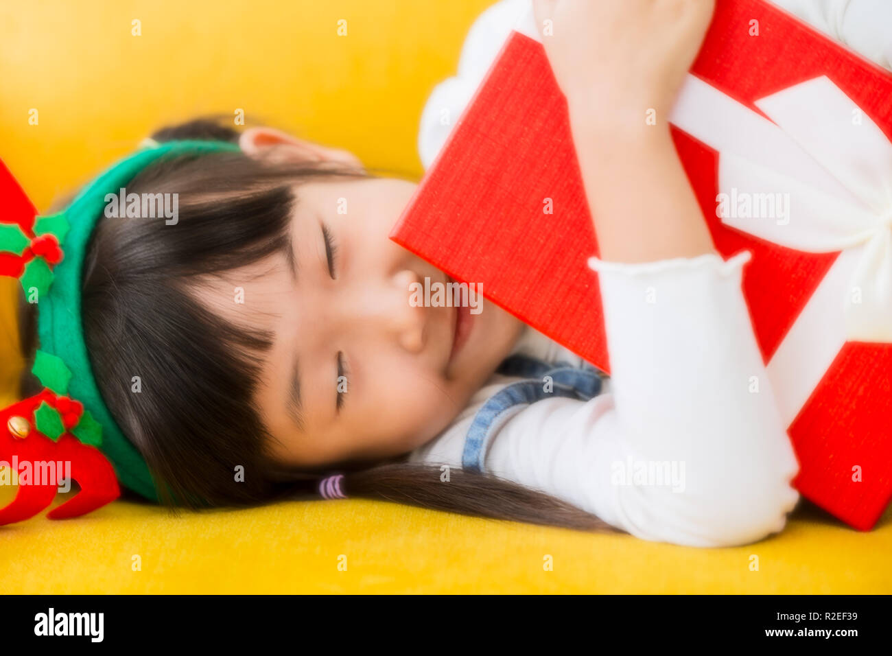 Lovely kid girl smiling eye fermer hug bras boîte cadeau de nouvel an avec un effet de rêve. Banque D'Images