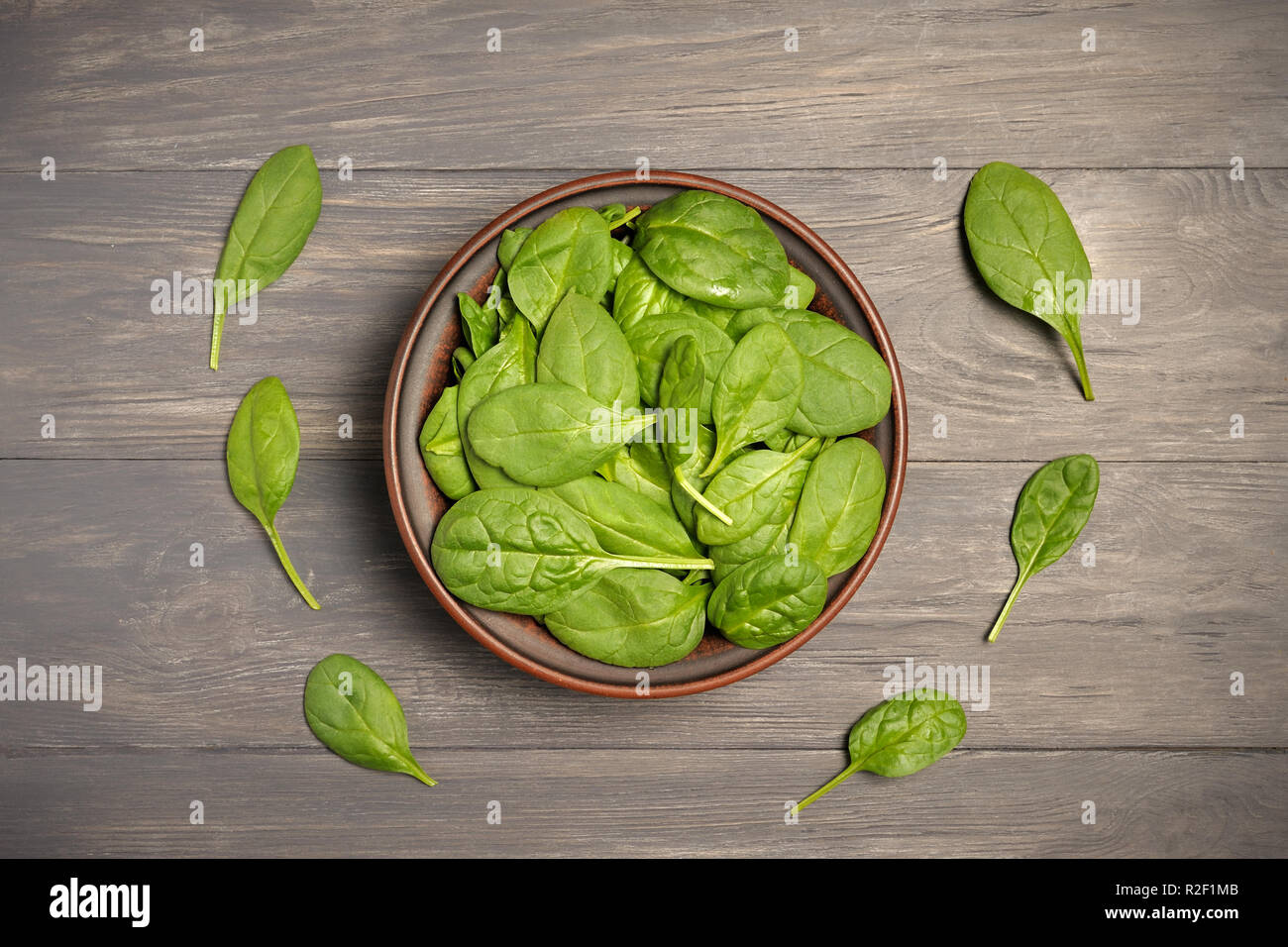 Les feuilles d'épinards verts en brun foncé sur le bol alimentaire feuillus comme arrière-plan un concept de saine alimentation frais jardin produisent des aliments biologiques comme un symbole de Banque D'Images