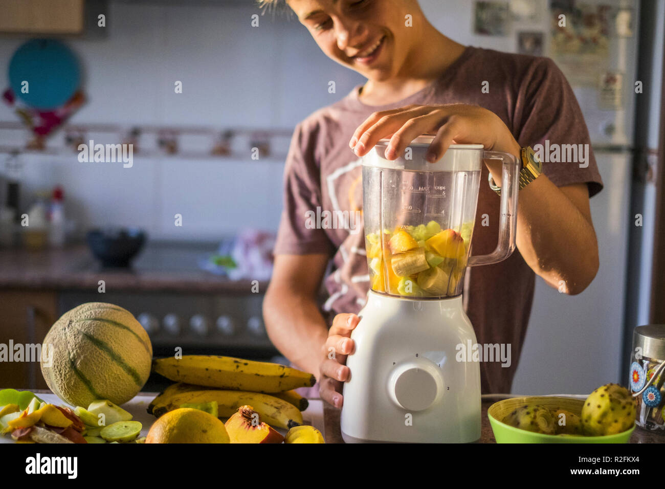 Handsome young caucasian adolescents la préparation d'une boisson lisse à la maison avec un mélange de fruits sains. secouant avec une machine dans la cuisine pour une boisson santé et nutrition idéal pour rester bien. belle vie pour la génération Y Banque D'Images