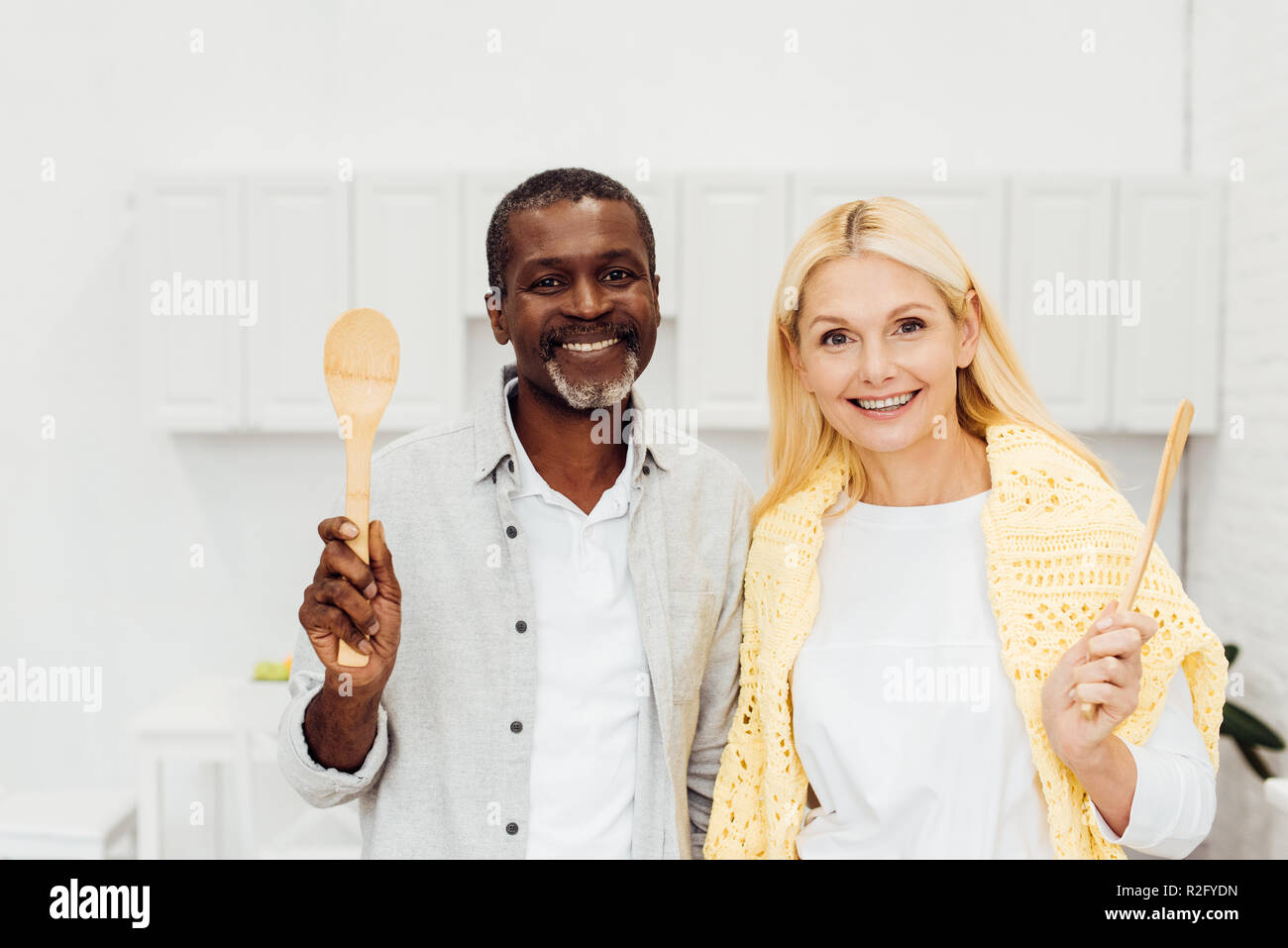 Happy smiling couple holding spatules en bois à cuisine Banque D'Images