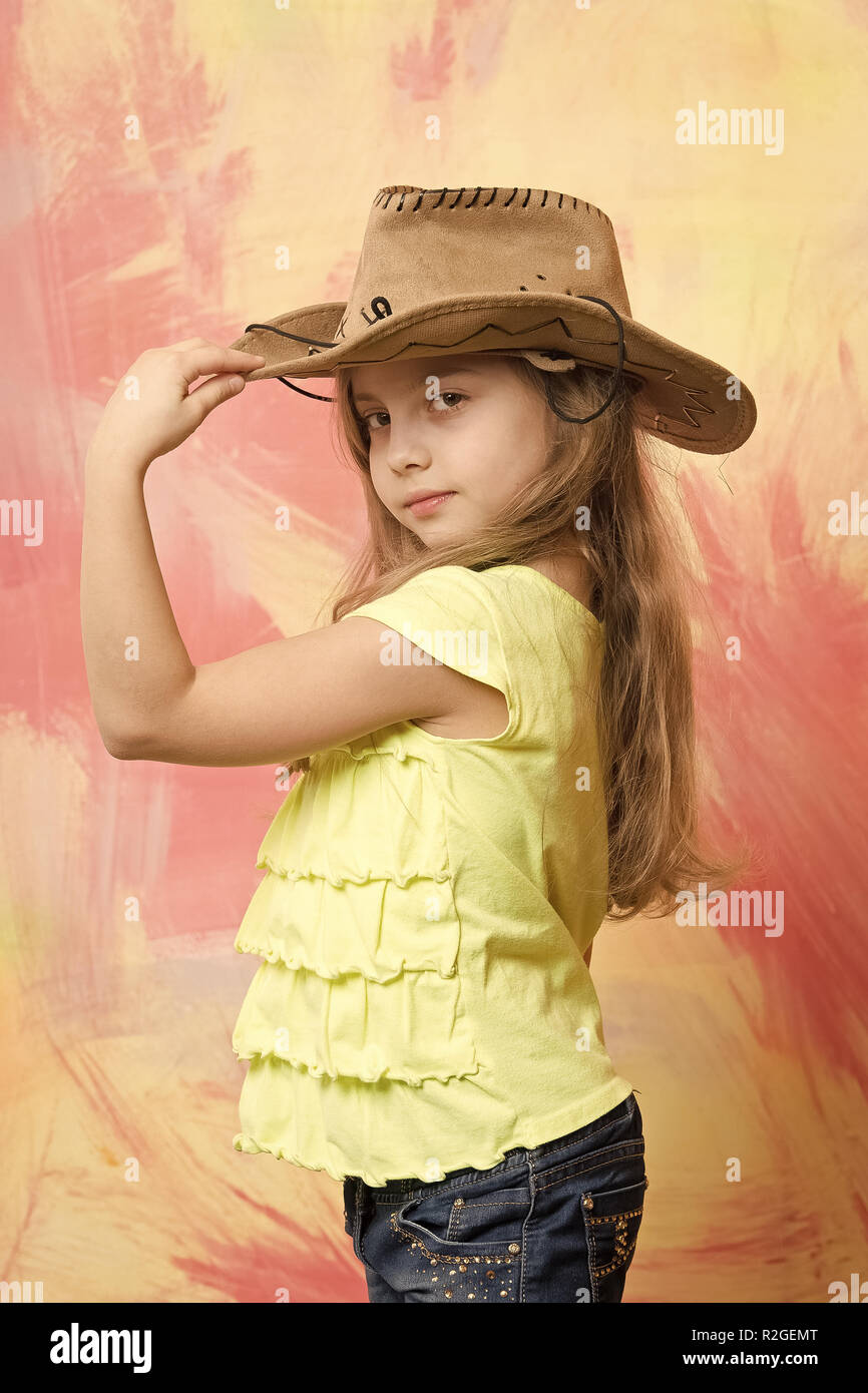 Petite fille dans cowboy ou cowgirl costume avec chapeau à la main posée sur l'arrière-plan coloré Banque D'Images