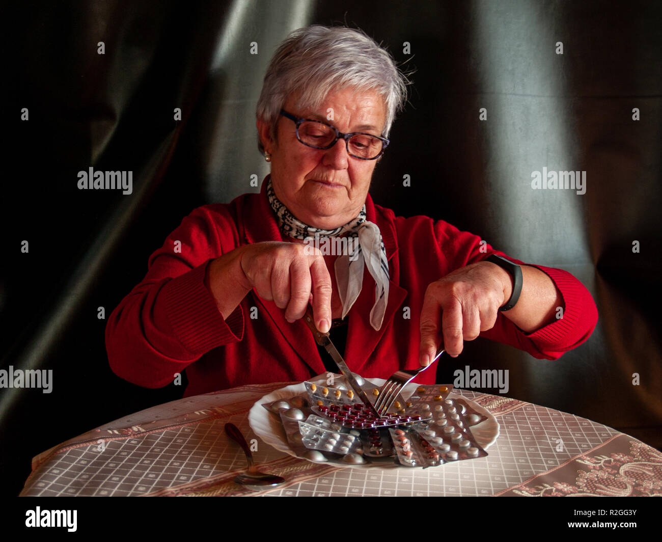 Concept de la médecine et des soins de santé. A senior woman cutting plusieurs comprimés de pilules de manger dans son assiette Banque D'Images