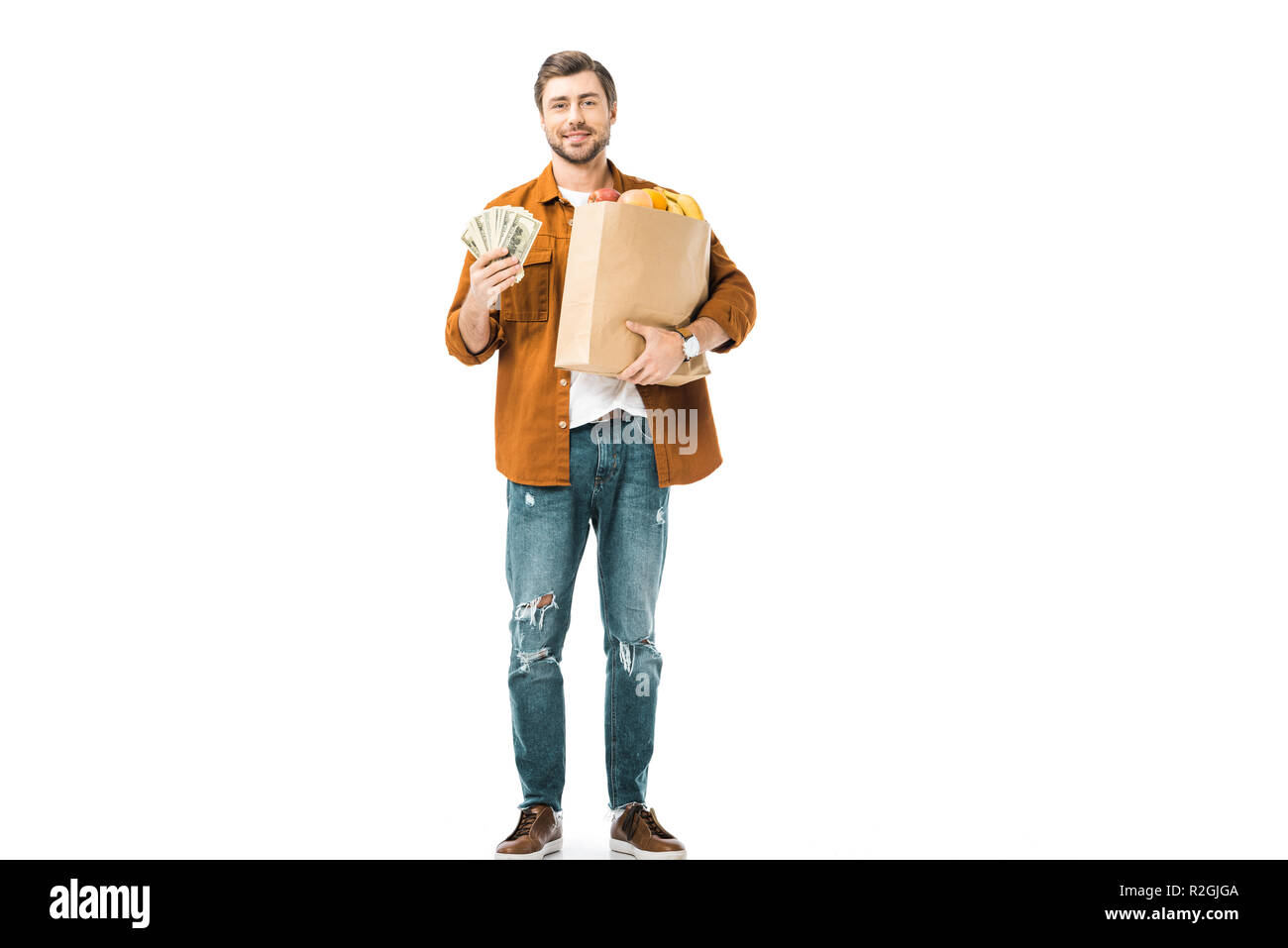 Homme montrant l'argent comptant et holding paper sac plein de produits isolated on white Banque D'Images