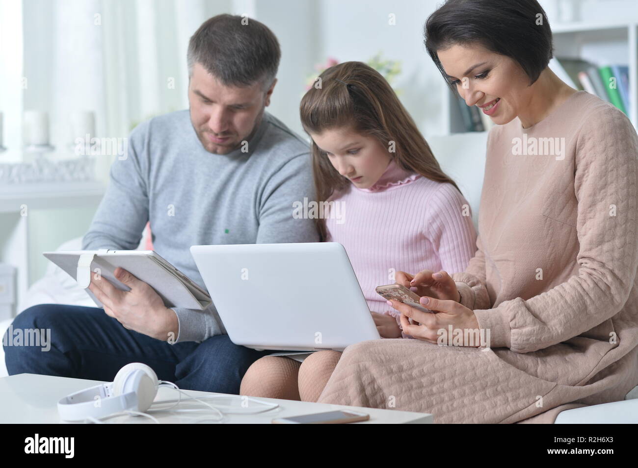 Heureux parents et sa fille à l'aide d'appareils numériques Banque D'Images