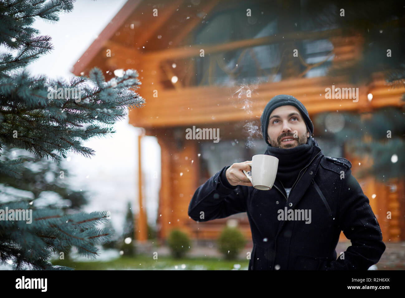 Homme avec boisson chaude à la neige qui tombe à Banque D'Images