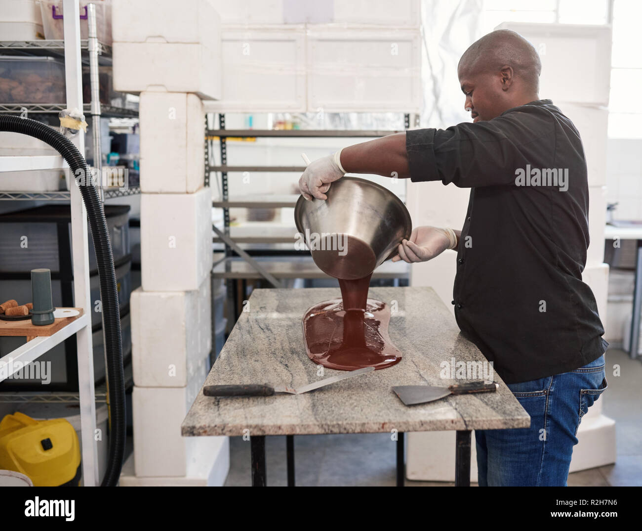 Chocolat artisanal pouring melted travailleur sur une table d'usine Banque D'Images