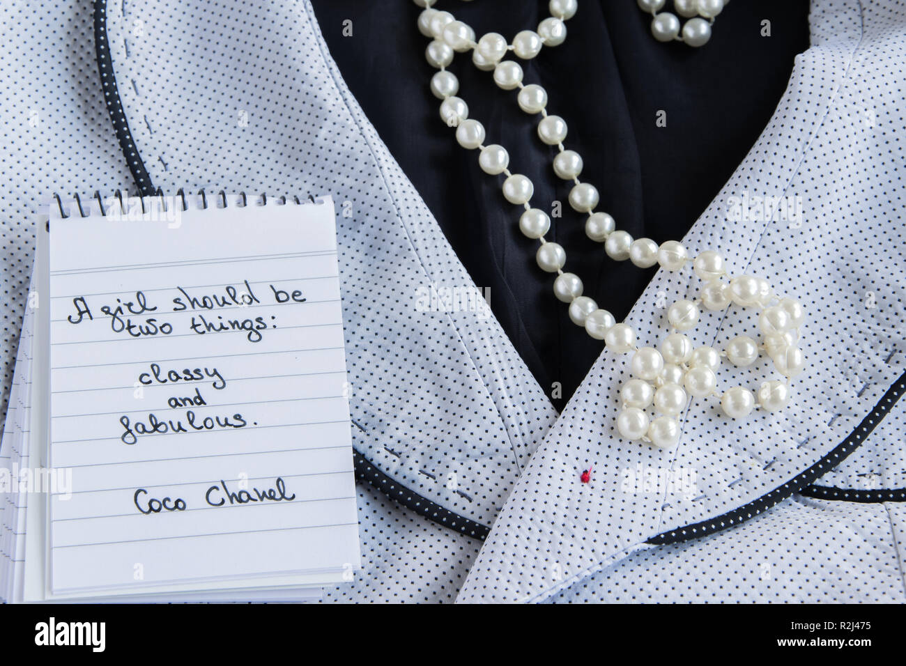 Coco Chanel précédemment écrit sur un note, pearl accessoires et une veste chic de phrase "une fille devrait être deux choses : chic et fabulou Photo Stock - Alamy