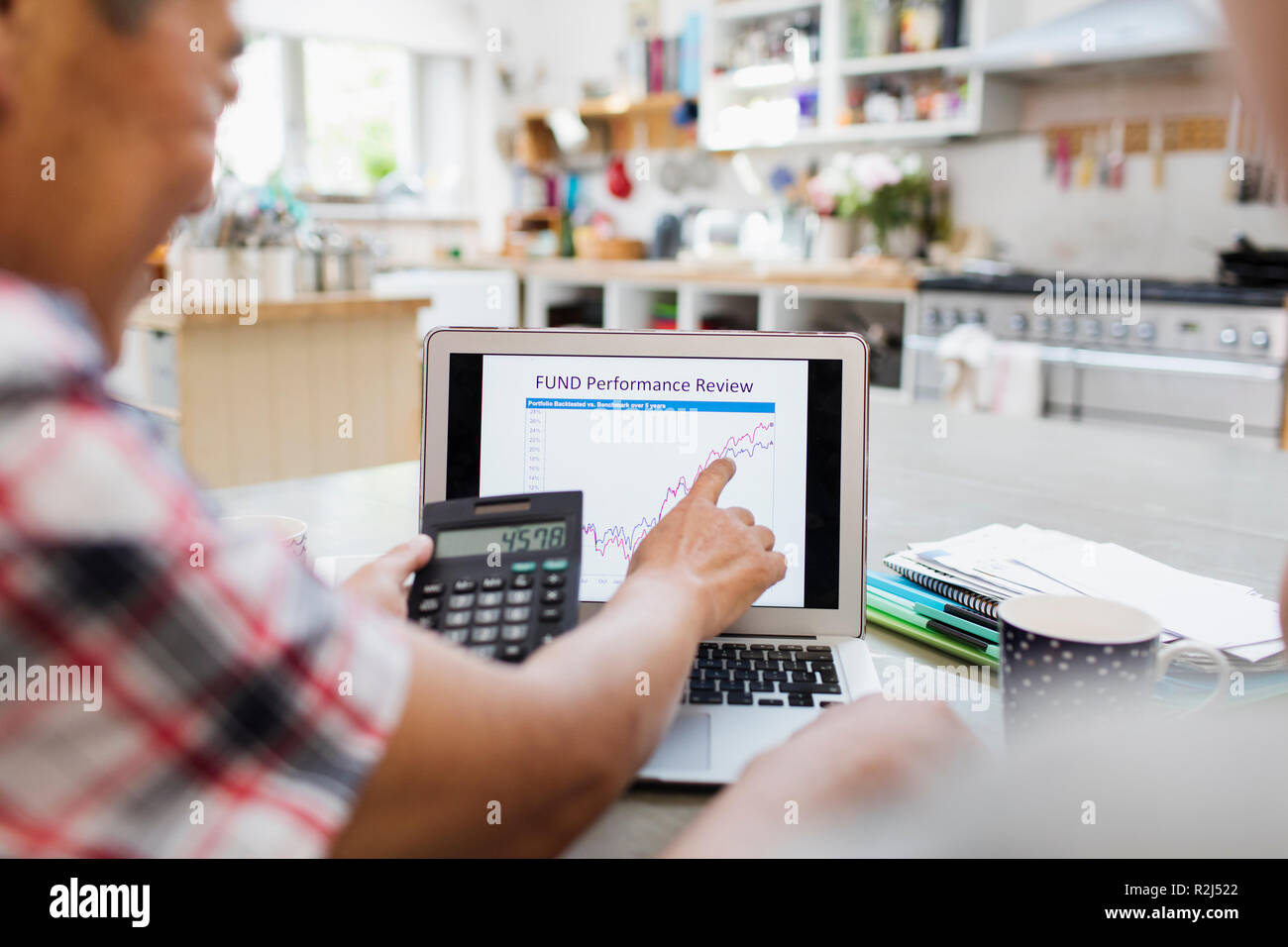 Man avec la calculatrice à l'investissement graphique sur ordinateur portable Banque D'Images