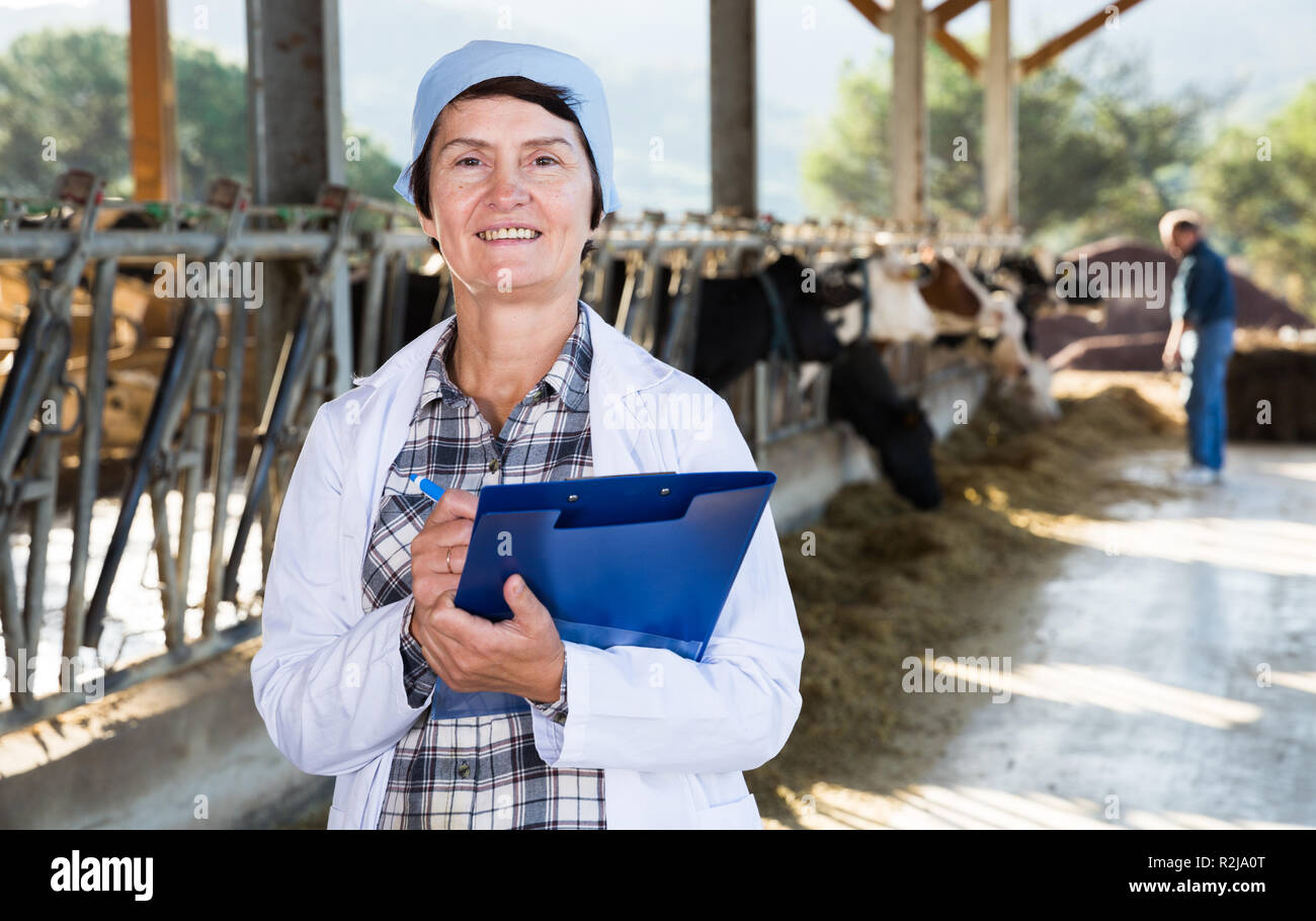Certains hauts femme vétérinaire avec presse-papiers travaillant sur la ferme de la vache Banque D'Images Certains hauts femme vétérinaire avec presse-papiers travaillant sur la ferme de la vache Banque D'Images