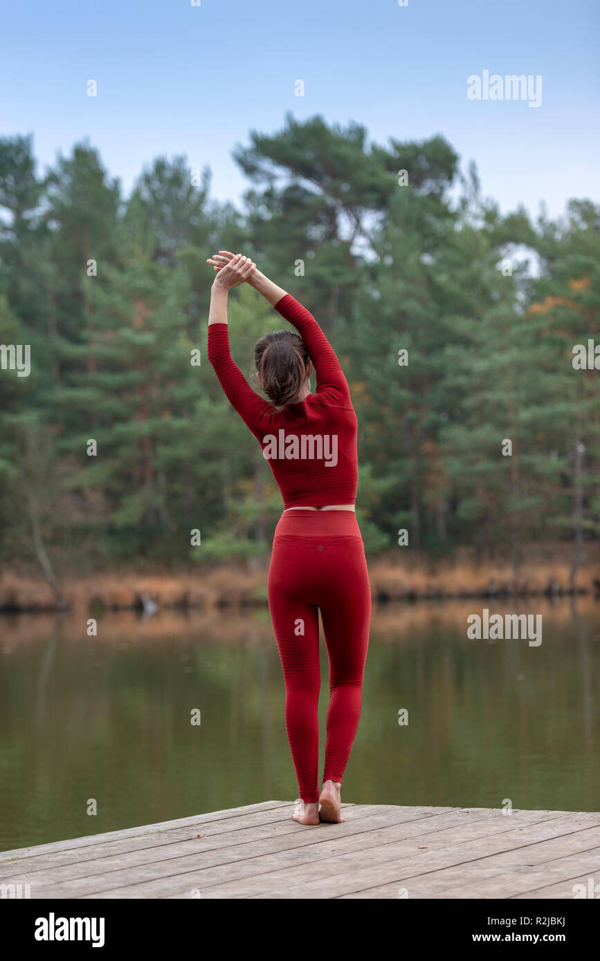 Femme debout sur une jetée à côté d'un lac qui s'étend et s'échauffer avant l'exercice à l'extérieur. Banque D'Images