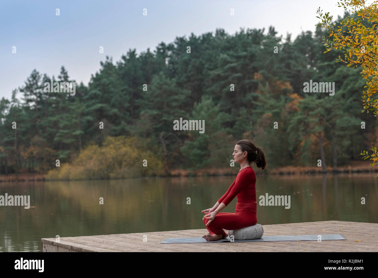 Woman sitting by a lake méditer et pratiquer le yoga Banque D'Images