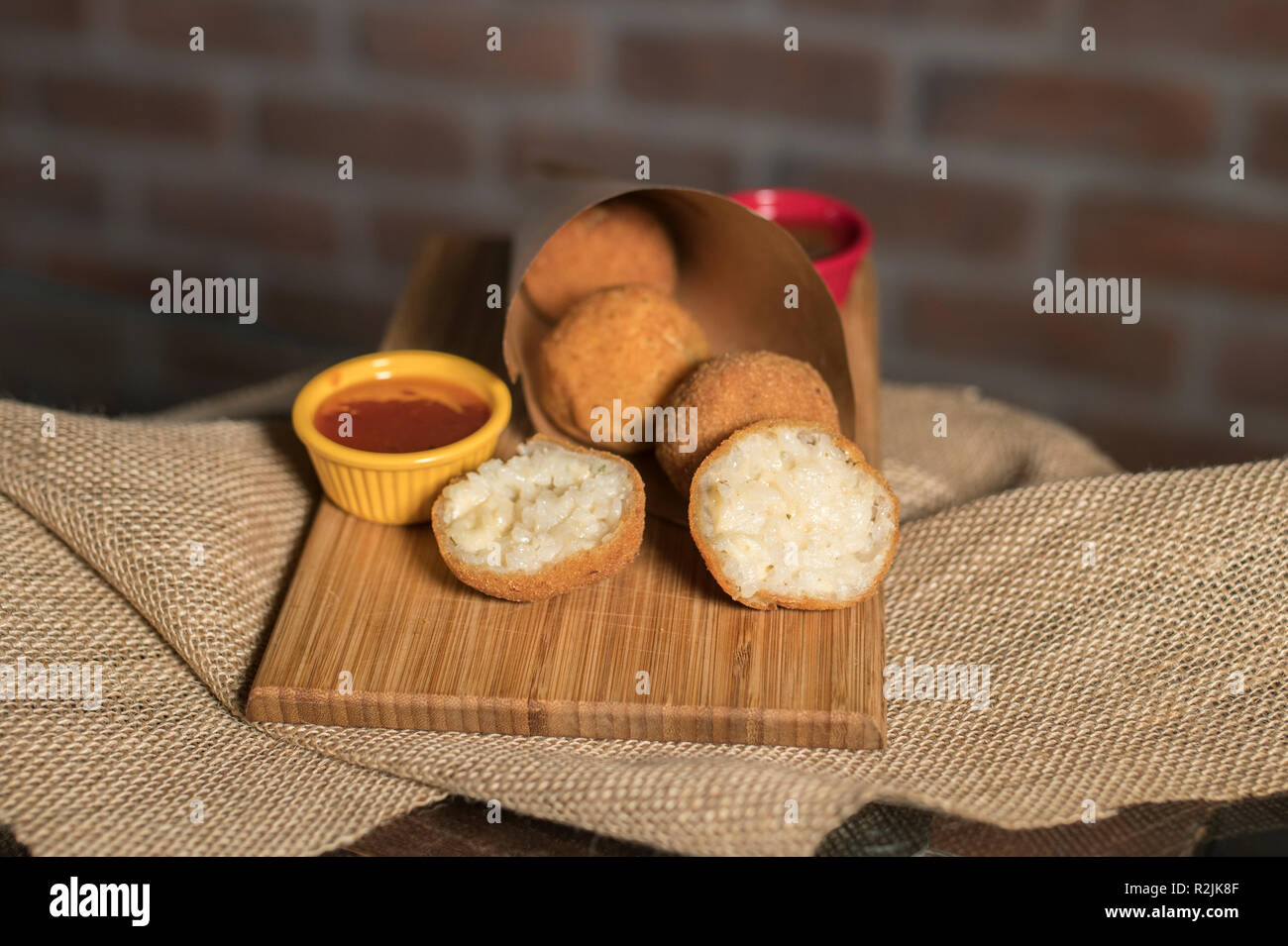 Boulettes frites avec deux sauces différentes sur la plaque en bois avec mur de brique Banque D'Images