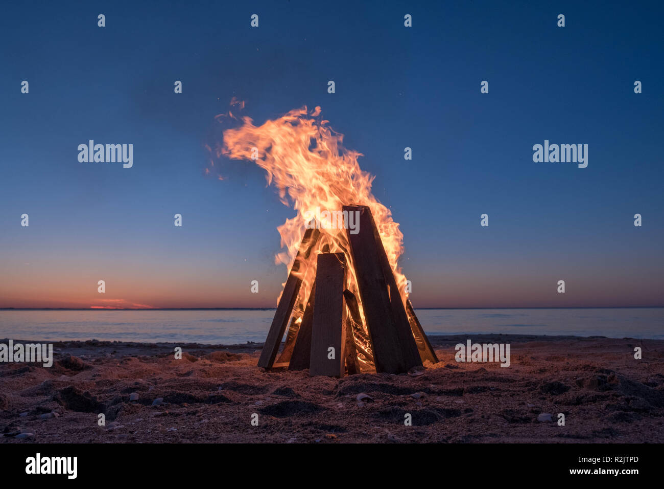 Feu de camp sur la plage au coucher du soleil Banque D'Images