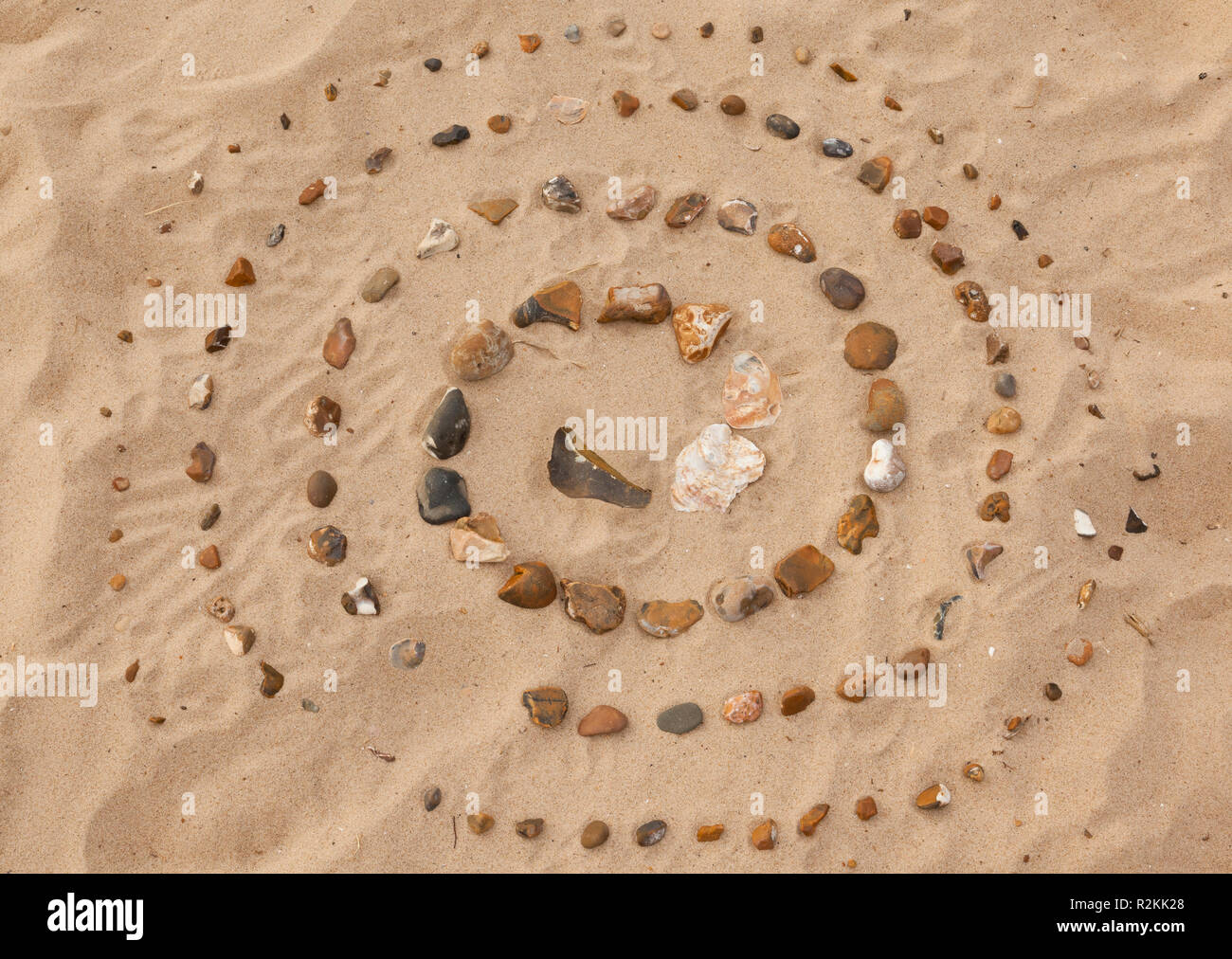 Un labyrinthe constitué de petites pierres sur une plage de sable Banque D'Images