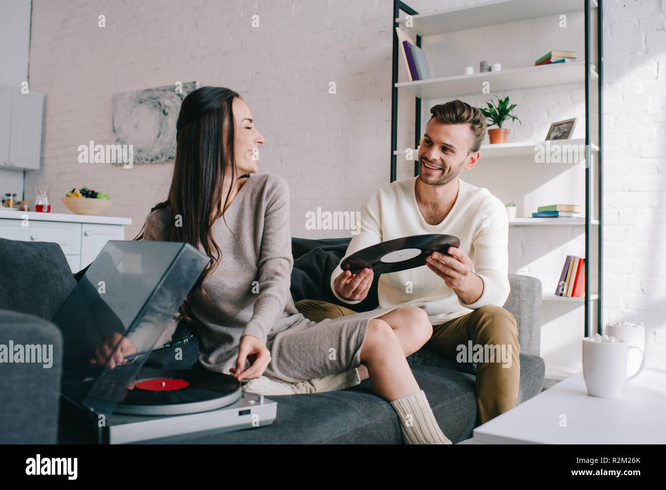 Jeune couple sympathique à l'écoute de la musique avec le vinyle à la maison phonographe Banque D'Images