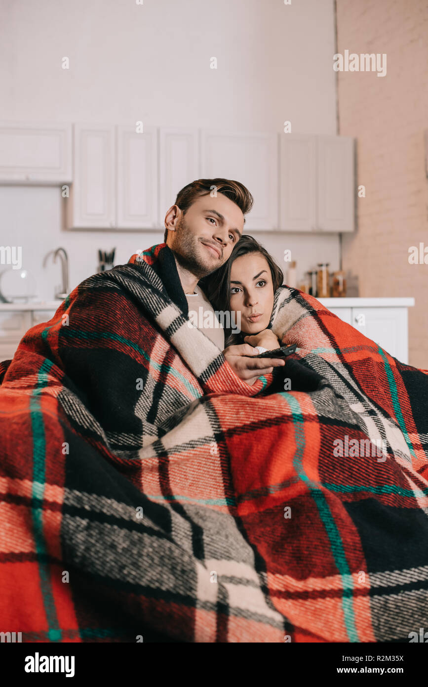 Jeune couple émotionnel relaxing on couch et regarder la télévision  ensemble tout en couvrant avec plaid Photo Stock - Alamy