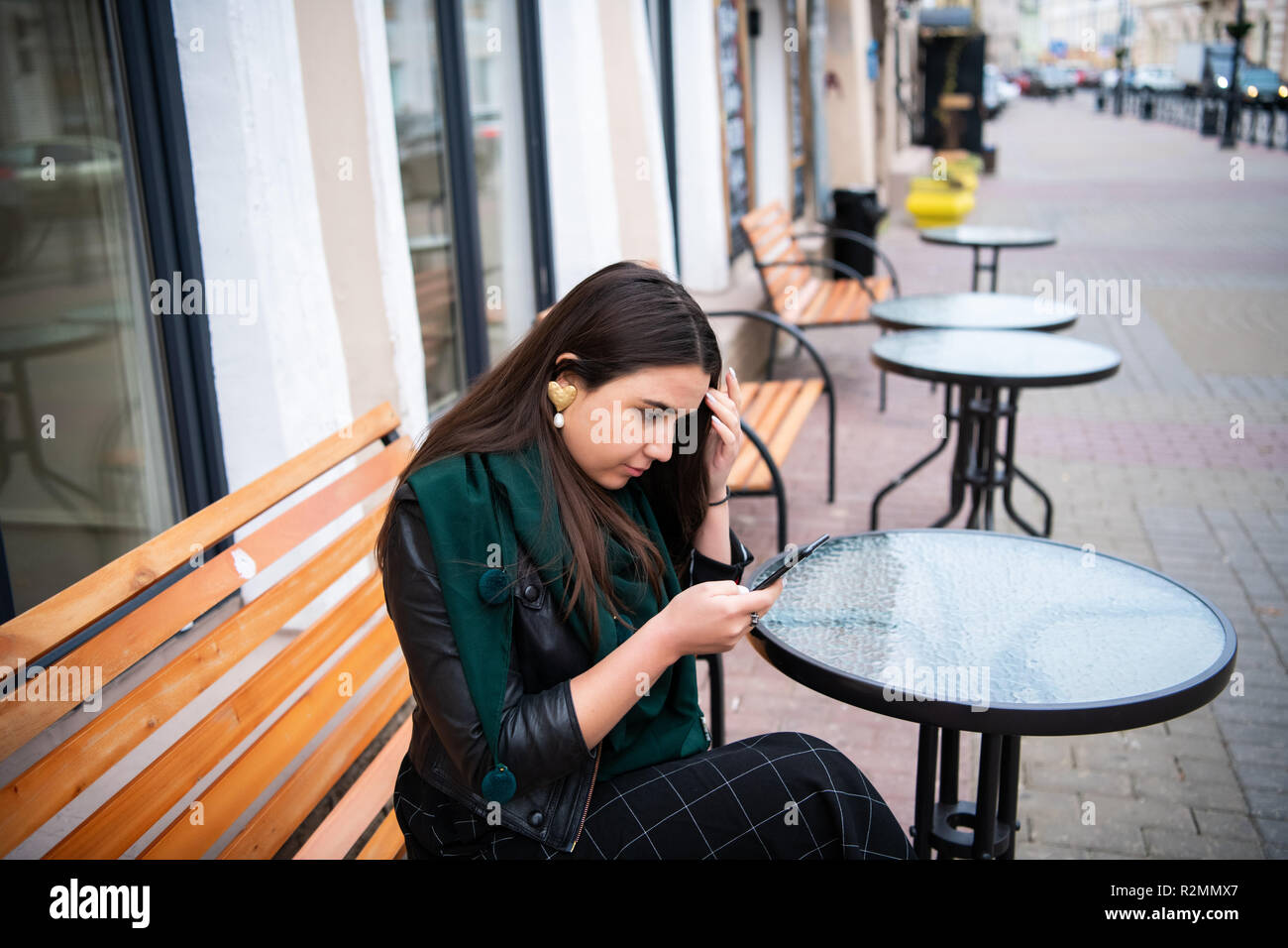 Woman looking at smartphone à street cafe sentiment contrarié. Banque D'Images