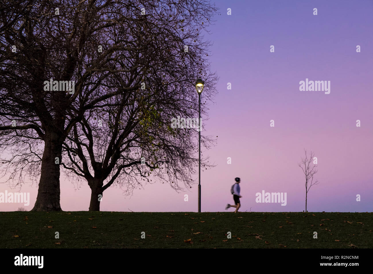 Personne le jogging. Homme court ou de formation dans un parc la nuit, Nottingham, England, UK Banque D'Images