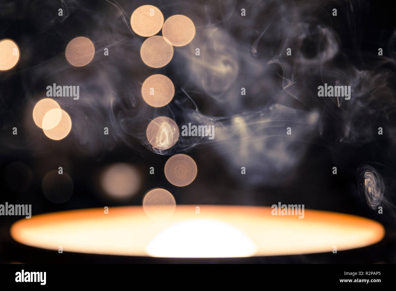 Résumé photo d'une lampe de table tourné à 180 degrés, la fumée de cigarette au premier plan, Flou, chaîne de lumières, fond sombre Banque D'Images