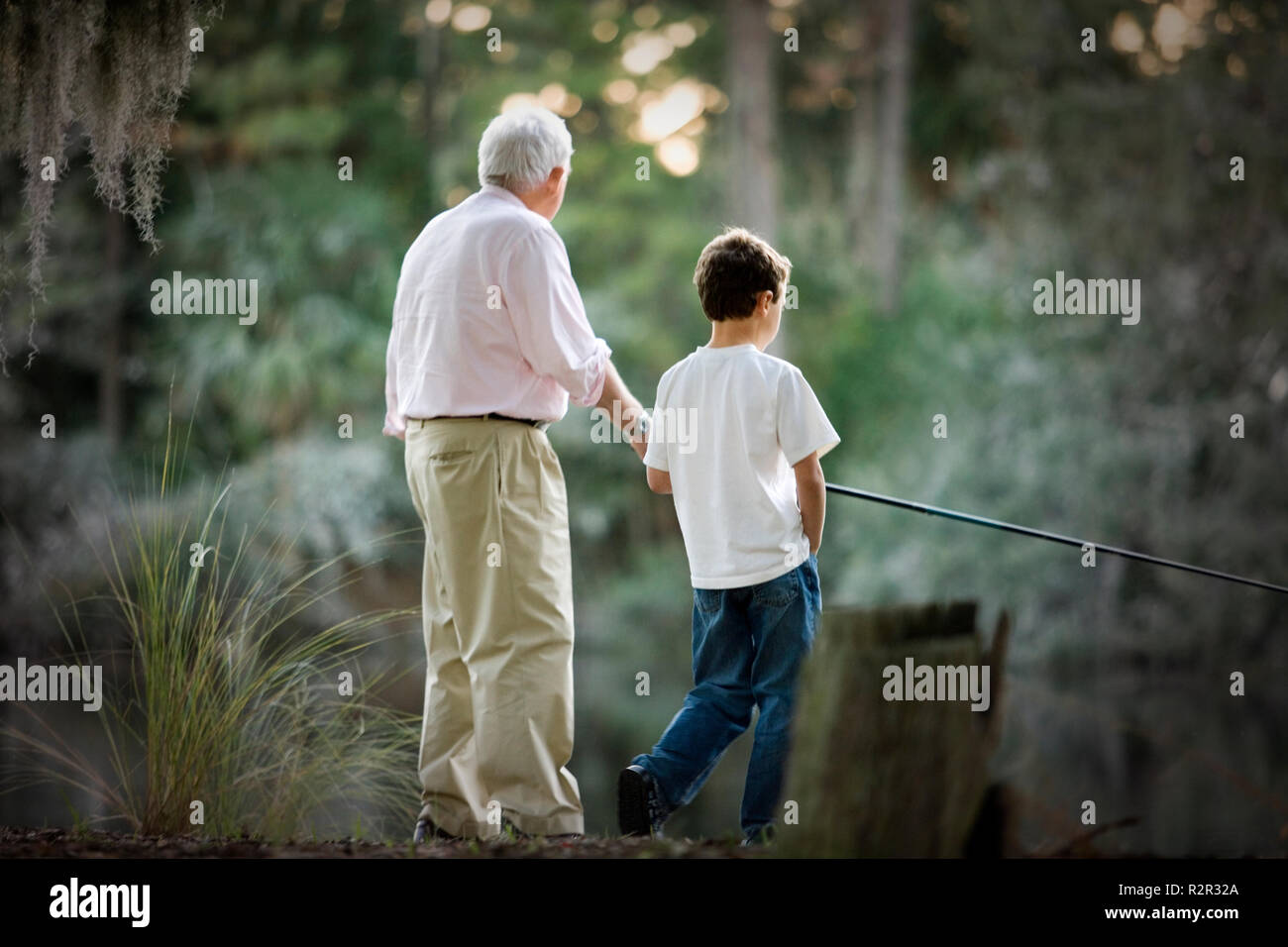 Senior adult man la pêche dans un lac avec son jeune petit-fils. Banque D'Images