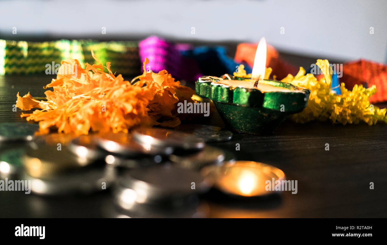 Diya allumé décorées de fleurs et de pièces de monnaie pour célébrer diwali et dhanteras Banque D'Images