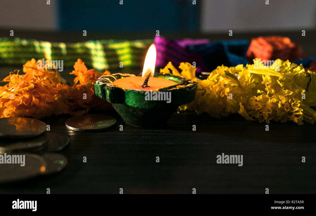 Diya allumé décorées de fleurs et de pièces de monnaie pour célébrer diwali et dhanteras Banque D'Images