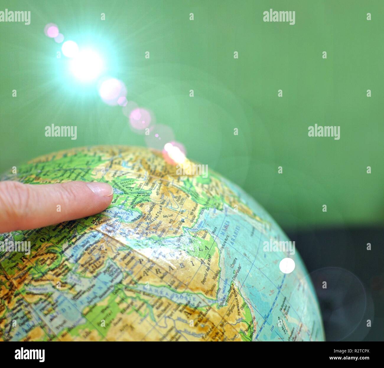 Gros plan d'une carte du monde globe avec son index sur elle. Concept de voyager, d'explorer ou de rechercher la destination. Lens Flare up side de gauche Banque D'Images