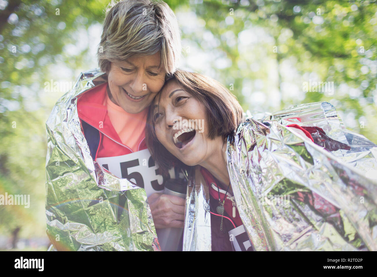 Happy active senior women friends hugging après le sport race, enveloppé dans une couverture thermique Banque D'Images