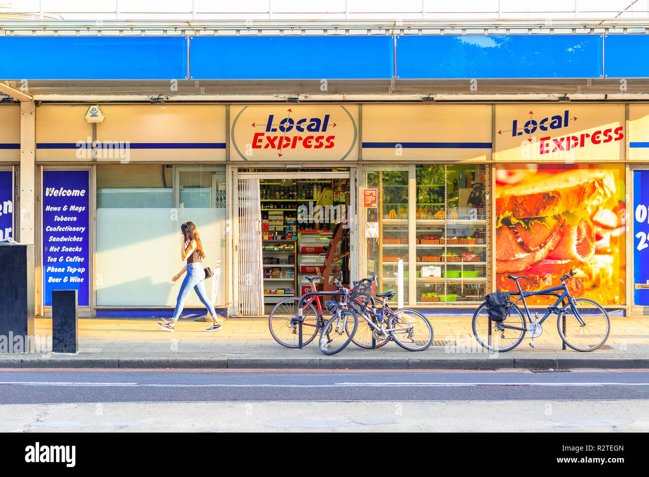 Londres, UK - 5 septembre 2018 - Le soleil jette une ombre sur une épicerie à Bermondsey avec une femme en passant par les piétons Banque D'Images