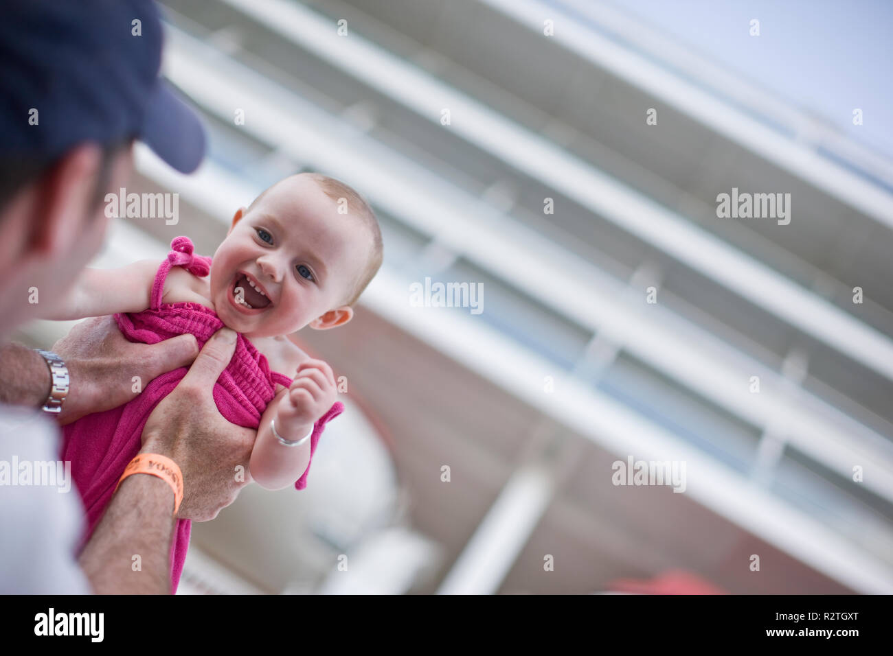 Portrait d'un jeune bébé rire lieu en altitude par son père. Banque D'Images