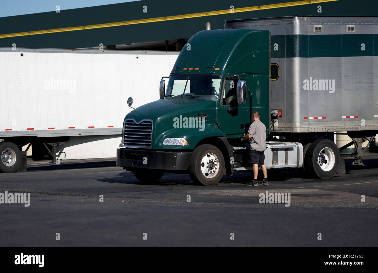 L'ouverture de la porte conducteur de camion de gros camion vert foncé semi cabine de jour avec camion semi-remorque van sec debout sur truck stop à côté de la station de carburant avec un autre s Banque D'Images