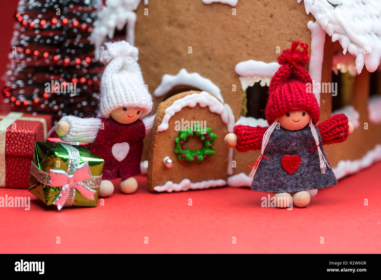 Maison avec des poupées et des biscuits de Noël sur fond rouge Banque D'Images