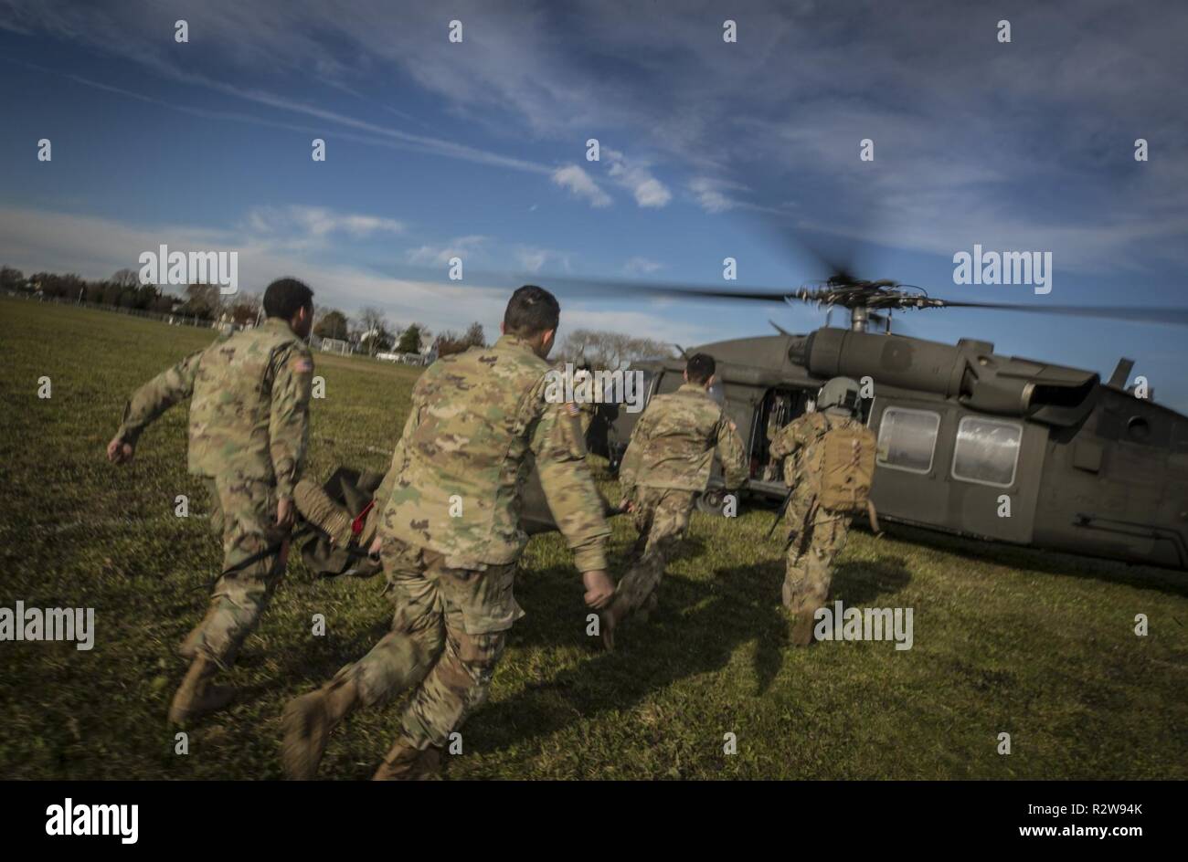 Les soldats de l'armée américaine charger une victime simulée sur un UH-60L Black Hawk du New Jersey le détachement de la Garde Nationale 2, la Compagnie Charlie, 1-171st Soutien général du bataillon de l'aviation, au cours de l'évacuation médicale formation sur Sea Girt, N.J., le 14 novembre 2018. Banque D'Images